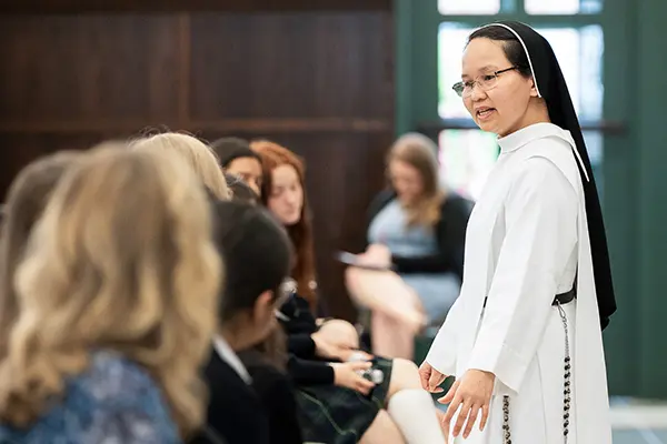 A nun speaks to a group of girls.